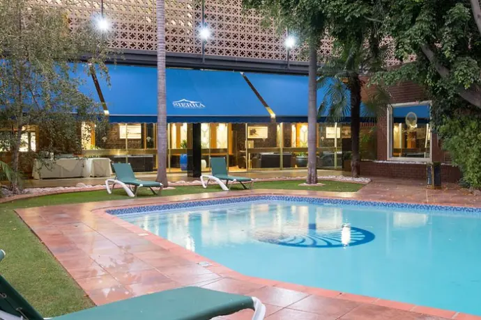 Outdoor swimming pool area at the former Burgers Park Hotel with lounge chairs