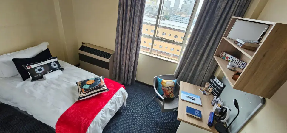 Fully furnished student room with study desk, single bed, and city view at Burgers Park Student Hotel